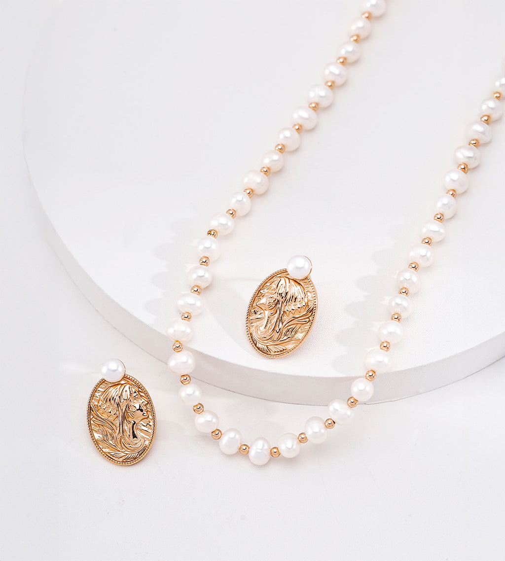 Vintage Gold portrait pearl earrings styled beside a white pearl necklace with gold-tone spacer beads on a white display
