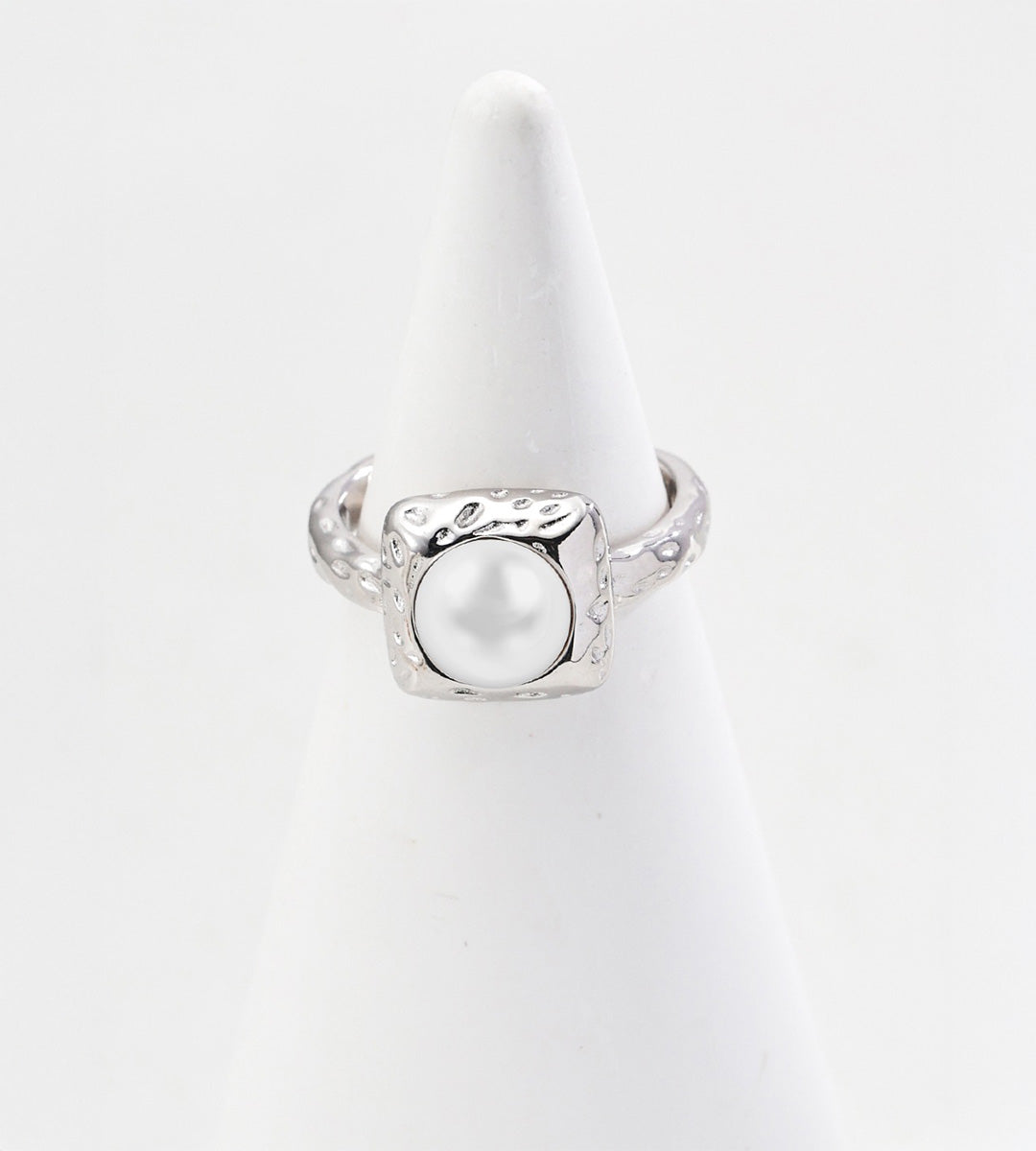 Silver-tone pearl ring with a square hammered-texture frame and matching textured band on a white cone display.
