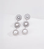 Silver-tone three-tier pearl drop earrings with pearl centres and textured circular frames on a white display.