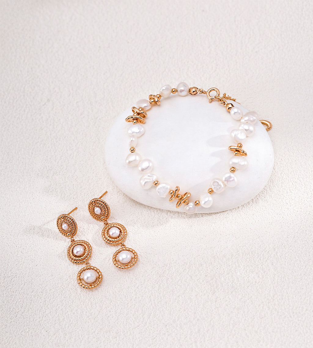 Vintage Gold three-tier pearl drop earrings displayed beside a pearl bracelet with gold-tone accents on a white background.