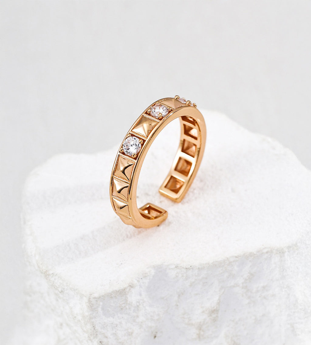 Vintage Gold open ring with pyramid-shaped rivets and round cubic zirconia, showing its hollow inner band on a white stone display.