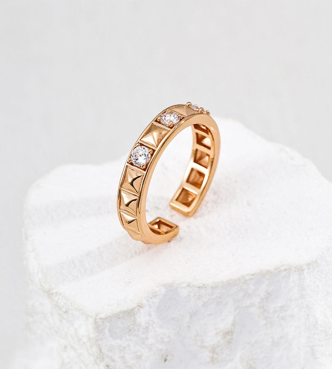 Vintage Gold open ring with pyramid-shaped rivets and round cubic zirconia, showing its hollow inner band on a white stone display.