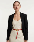 A woman modeling a black blazer over a cream slip dress, styled with a Red Slim Knotted Leather Belt with Gold Loop