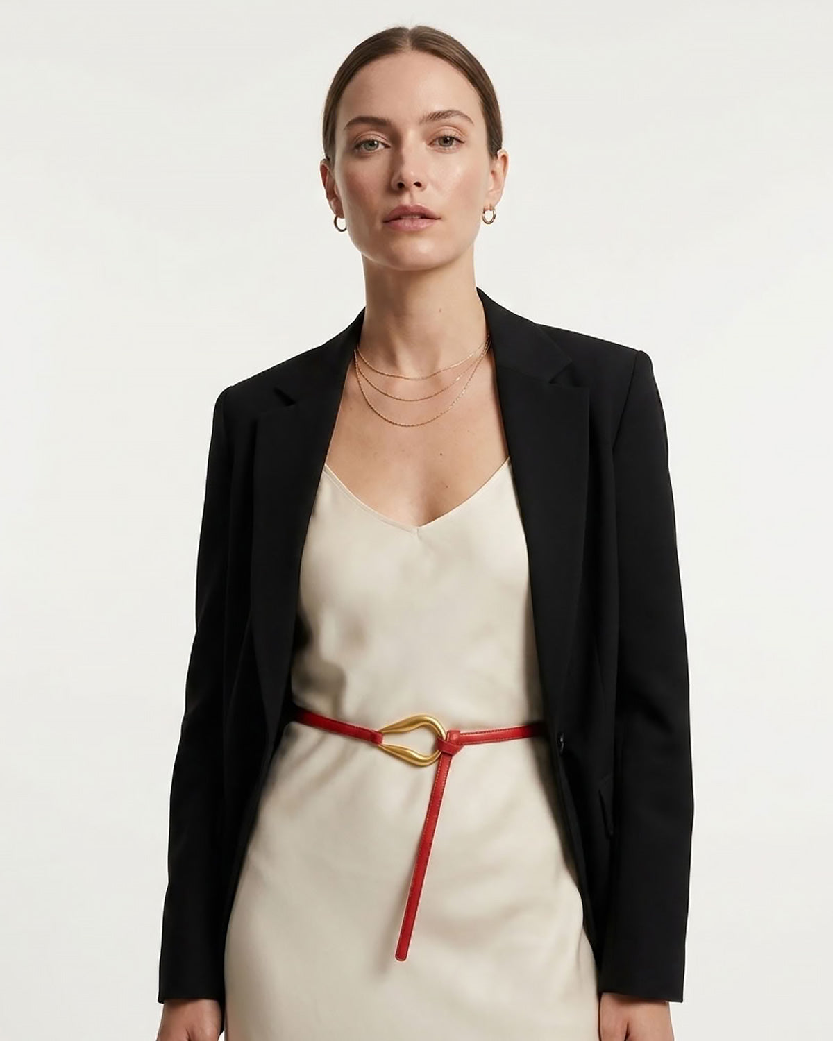 A woman modeling a black blazer over a cream slip dress, styled with a Red Slim Knotted Leather Belt with Gold Loop