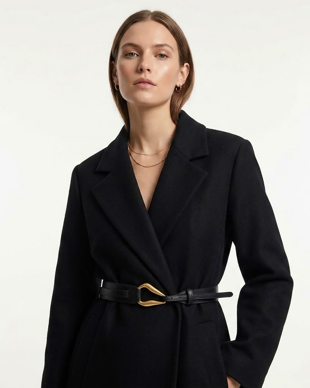 A woman wearing a black coat with a Black Leather Belt with a sculptural gold-toned hook clasp by BUCKLE Collective