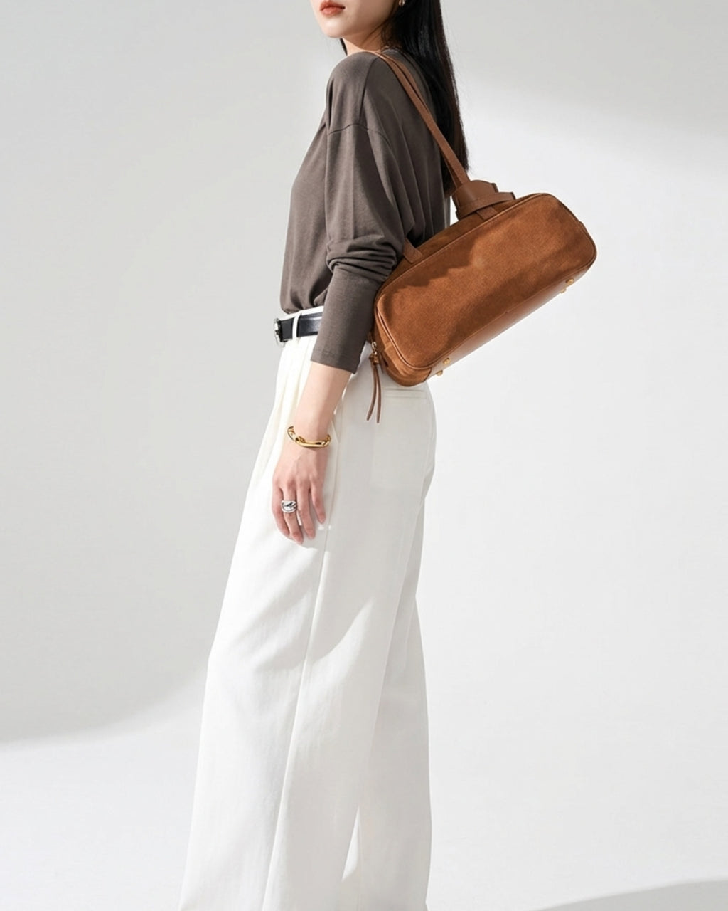 A woman in a stylish casual outfit wearing a Minimalist Suede Boston Handbag with Gold Details, Yellow-Brown Color