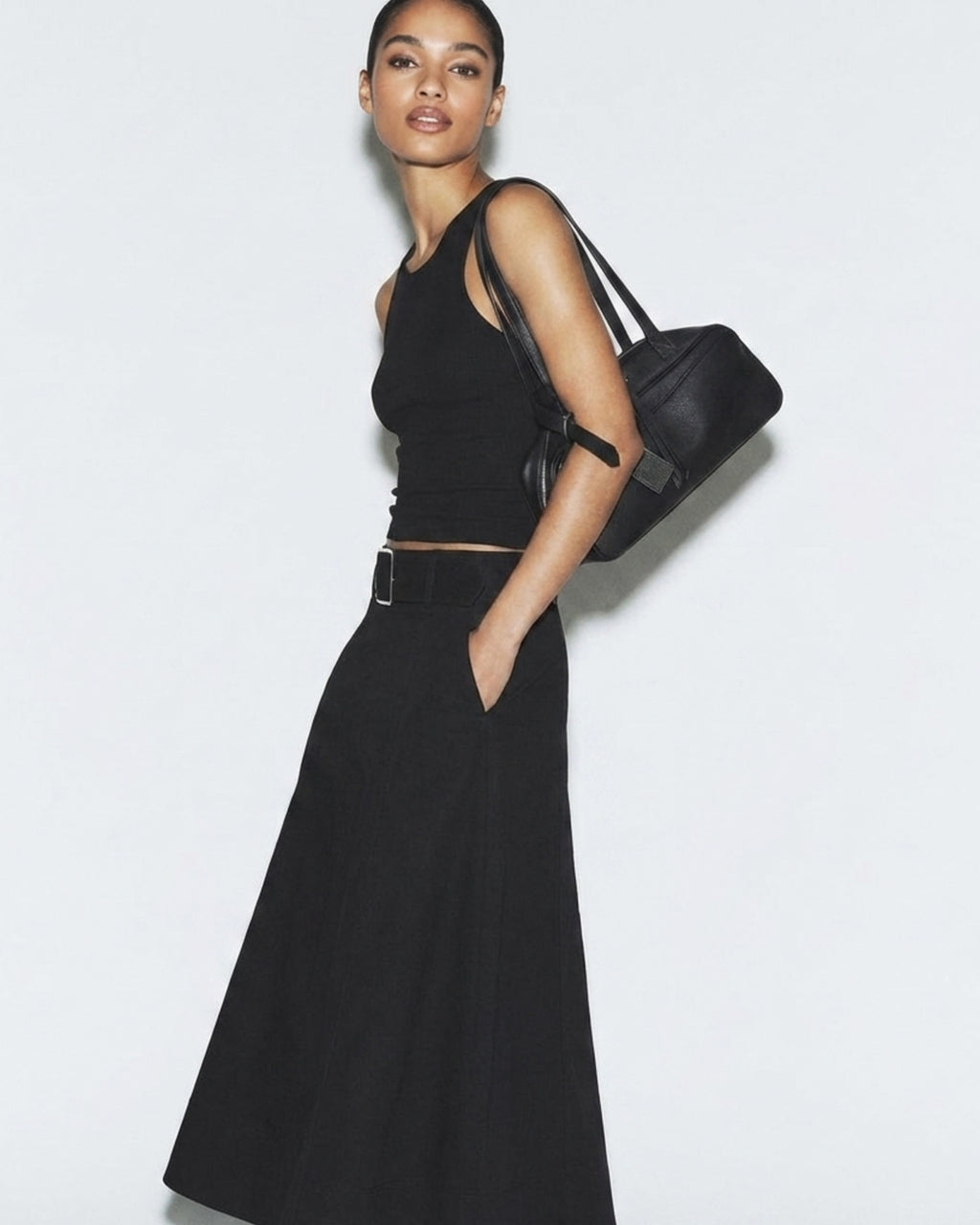Elegant woman in a stylish black outfit wearing a Sleek & Spacious Genuine Leather Boston Baguette Shoulder Bag in Black Color