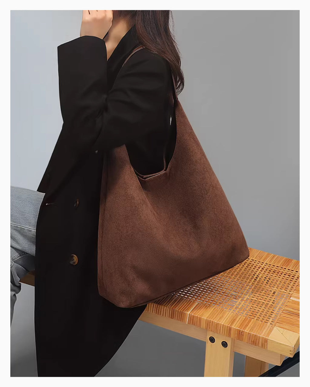 A woman in a black coat and jeans sitting on a wooden bench and wearing a Brown Suede Tote Bag with Vegan Faux leather single shoulder strap