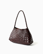 An angled view of a woven leather shoulder bag with a single top handle in Coffee color