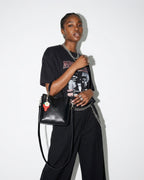 A woman wearing a black graphic t-shirt and holding a Black Genuine Leather Mini Tote Crossbody Bag with Strawberry and Floral Charm