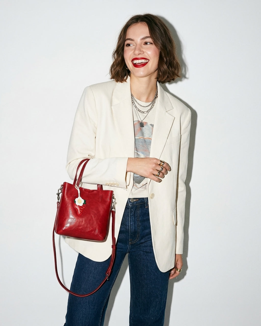 Woman in a stylish casual outfit holding a Red Genuine Leather Mini Tote Crossbody Bag with Strawberry and Floral Charm