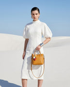 Woman in a white fashion-forward outfit holding a Genuine Leather Yellow Mini Tote Crossbody Bag with Strawberry and Floral Charm