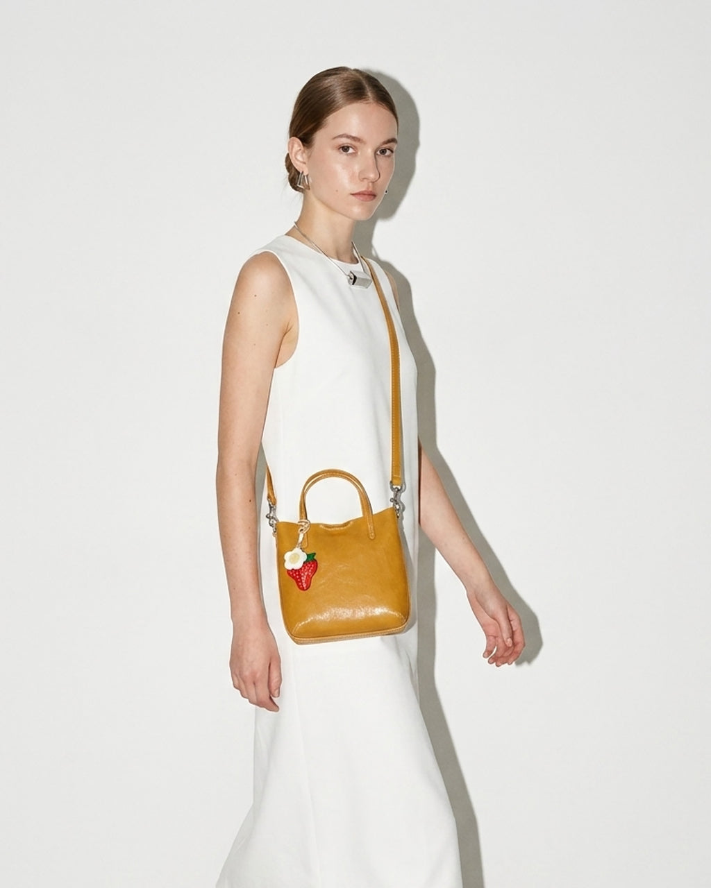 Woman carries a Honey Yellow Genuine Leather Mini Tote Crossbody Bag with Strawberry and Floral Charm