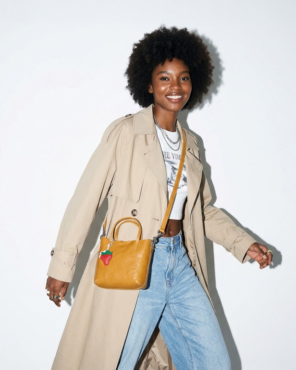 A woman in a minimalistic white dress carries a Honey Yellow Genuine Leather Mini Tote Crossbody Bag with Strawberry and Floral Charm