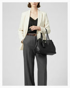 Woman in a smart-casual outfit with an Elegant Genuine Leather Black Tote Bucket Bag with Spacious Interior, Stylish Knot Detail and detachable leather lipstick pouch