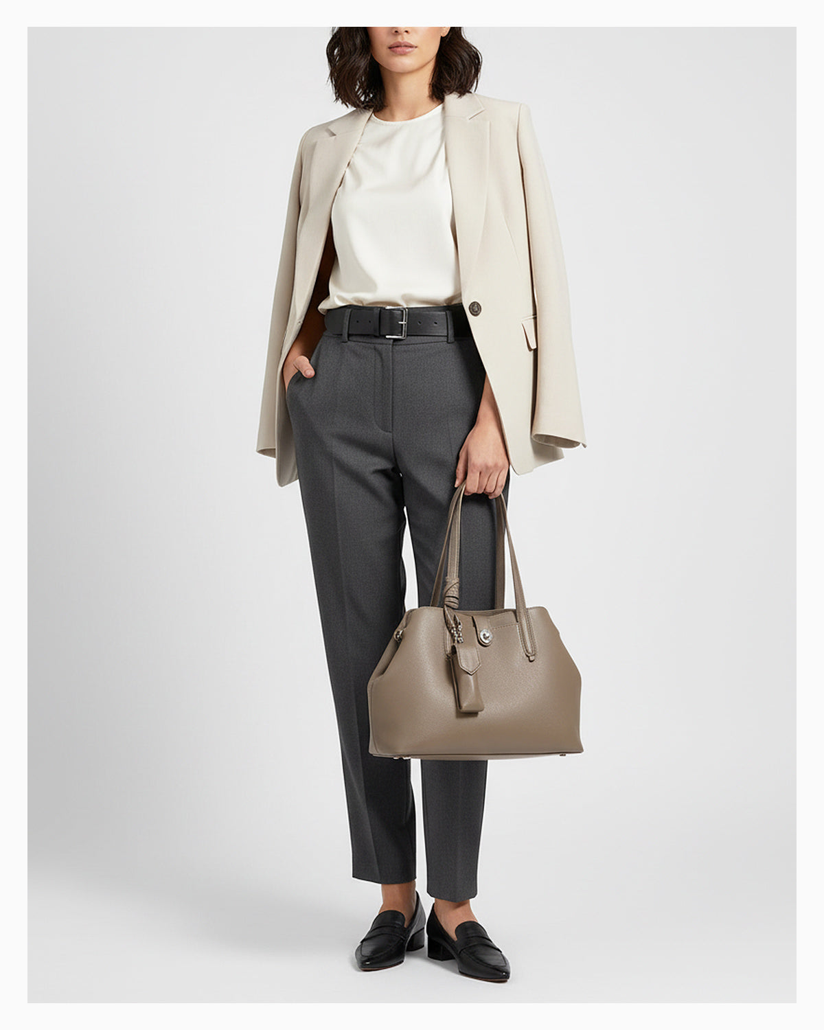A woman in a smart-casual outfit with an Elegant Genuine Leather Beige Gray Tote Bucket Bag with Spacious Interior and Detachable Leather Lipstick Pouch