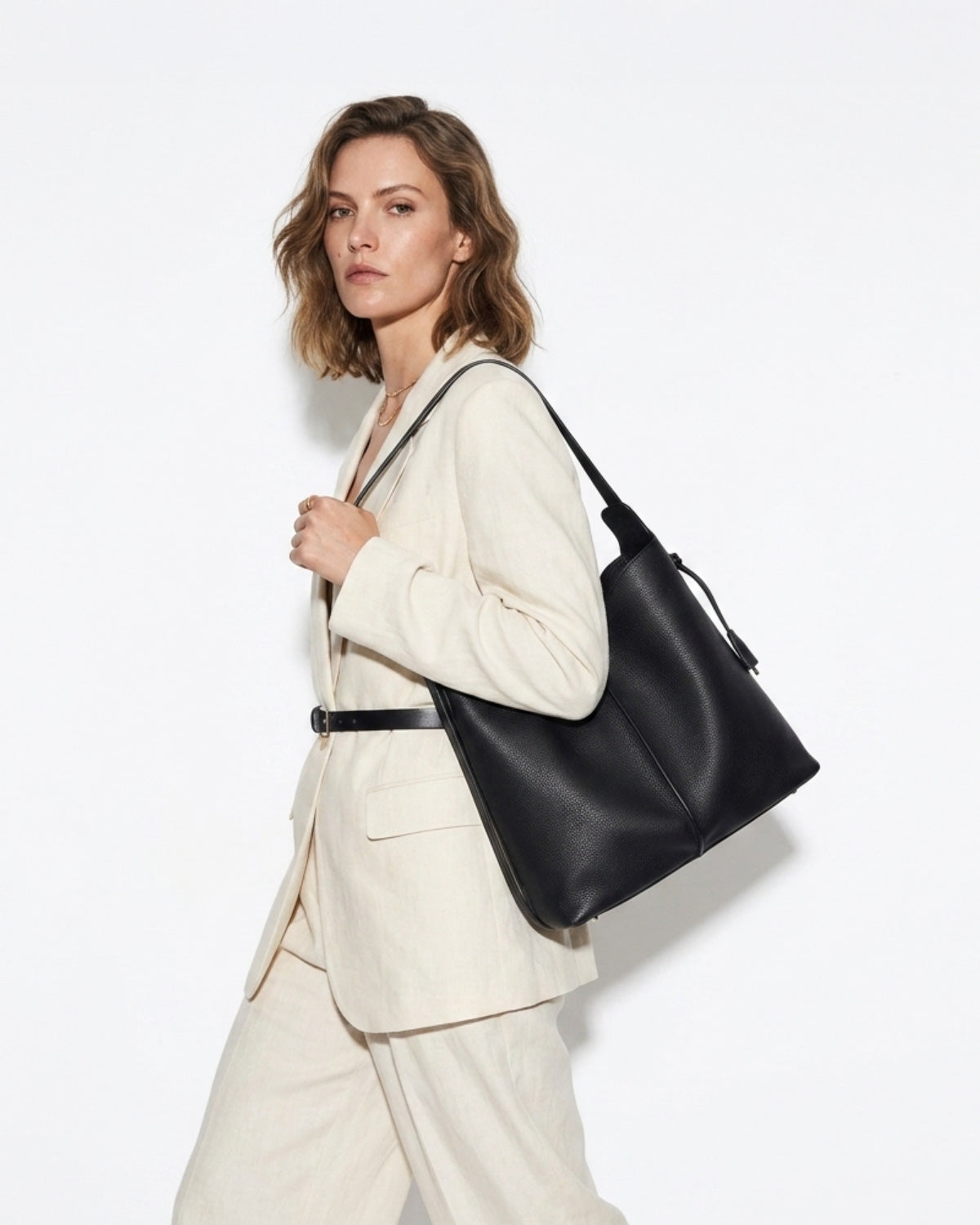 A stylish woman in a white fashion-forward outfit carries a Black Genuine Leather Tote Bag with an Adjustable Strap
