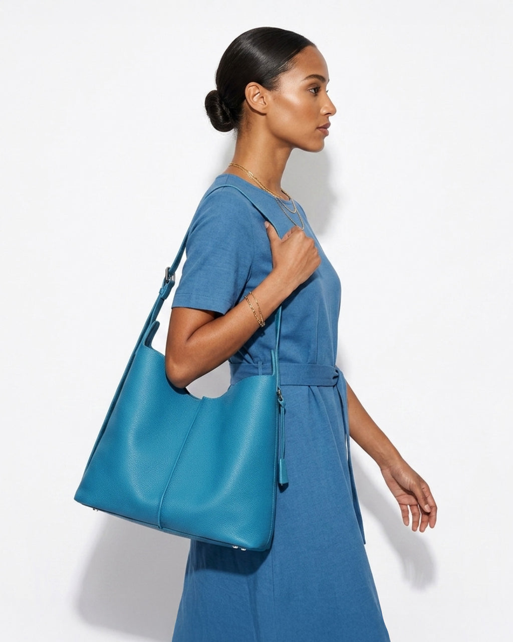 A stylish woman in a blue casual dress carries a Blue Genuine Leather Tote Bag with an Adjustable Strap and Inner Pouch