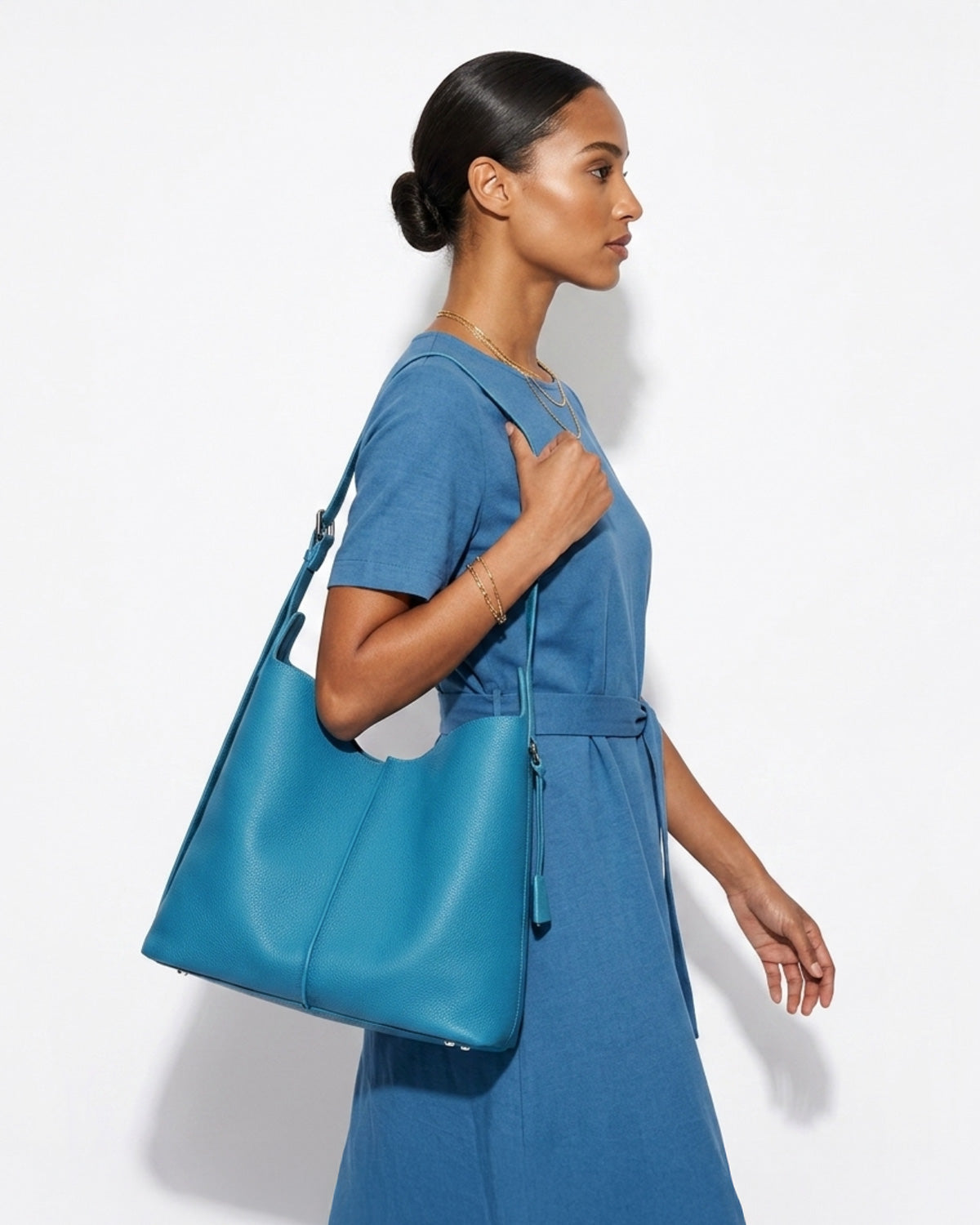 A stylish woman in a blue casual dress carries a Blue Genuine Leather Tote Bag with an Adjustable Strap and Inner Pouch