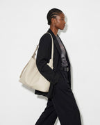 A stylish woman in a black fashion-forward outfit carries an Off-White Genuine Leather Tote Bag with an Adjustable Strap