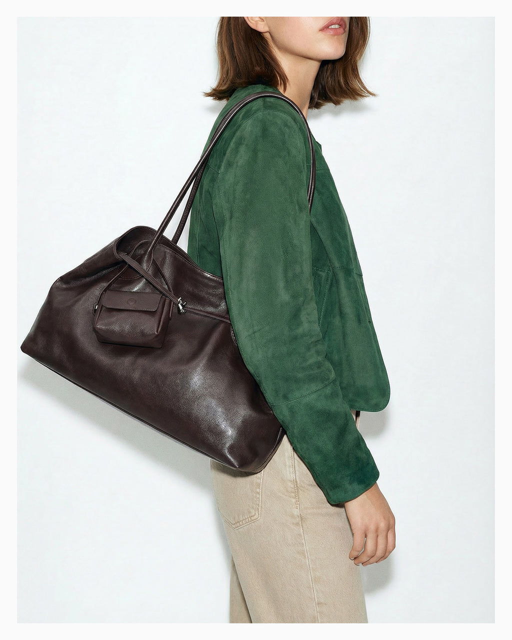 A chic woman in a stylish casual outfit carries a versatile genuine leather tote shoulder bag with a matching pouch in brown color