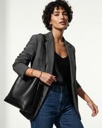 A woman in a stylish casual outfit with a jacket and jeans carries a Genuine Leather Minimalist Versatile Structured Bucket Bag in Black color