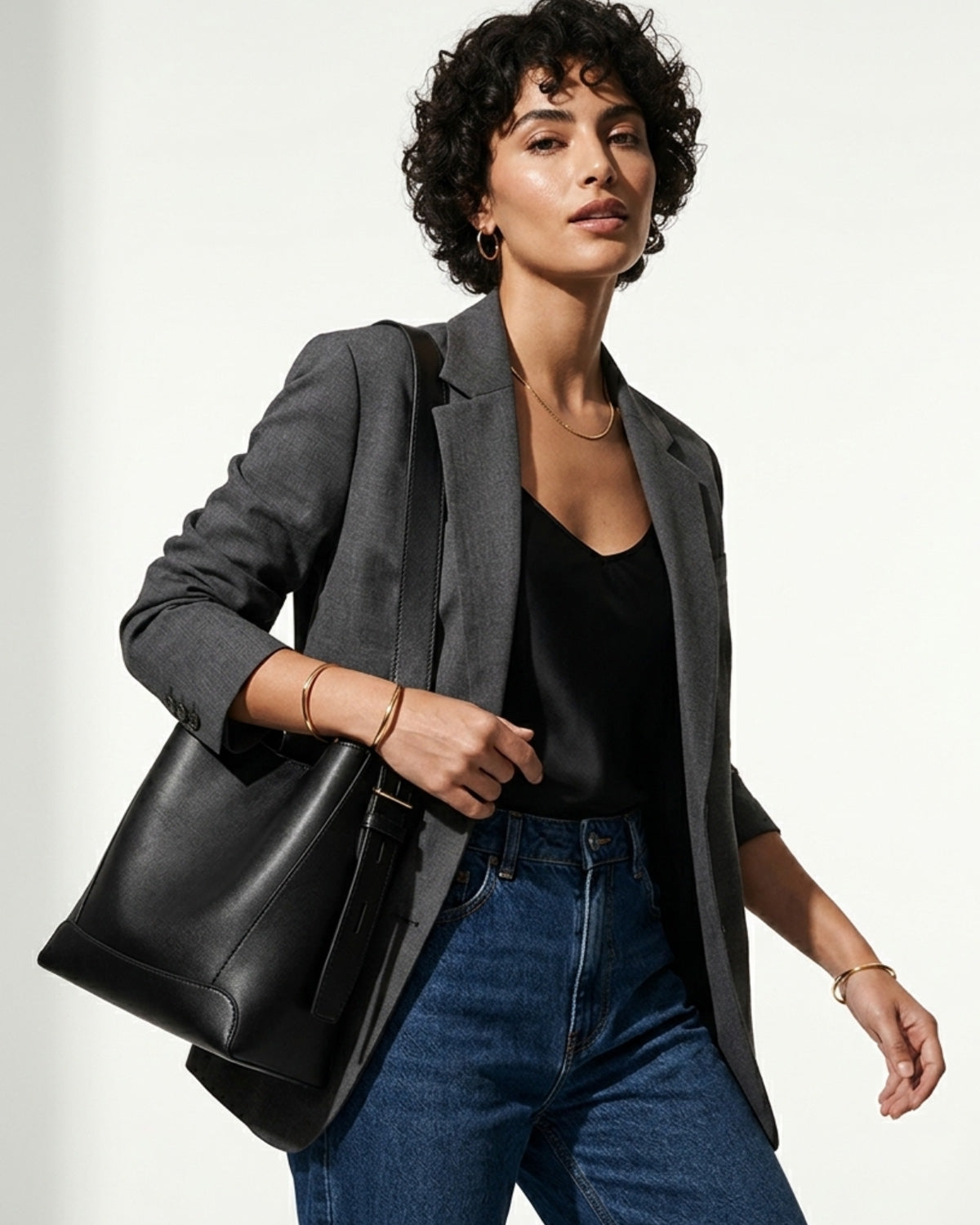 A woman in a stylish casual outfit with a jacket and jeans carries a Genuine Leather Minimalist Versatile Structured Bucket Bag in Black color