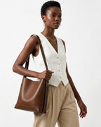 A woman in a trendy and stylish casual outfit carries a Genuine Leather Minimalist Versatile Structured Bucket Bag in Brown Color