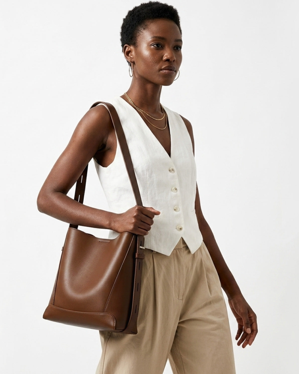 A woman in a trendy and stylish casual outfit carries a Genuine Leather Minimalist Versatile Structured Bucket Bag in Brown Color