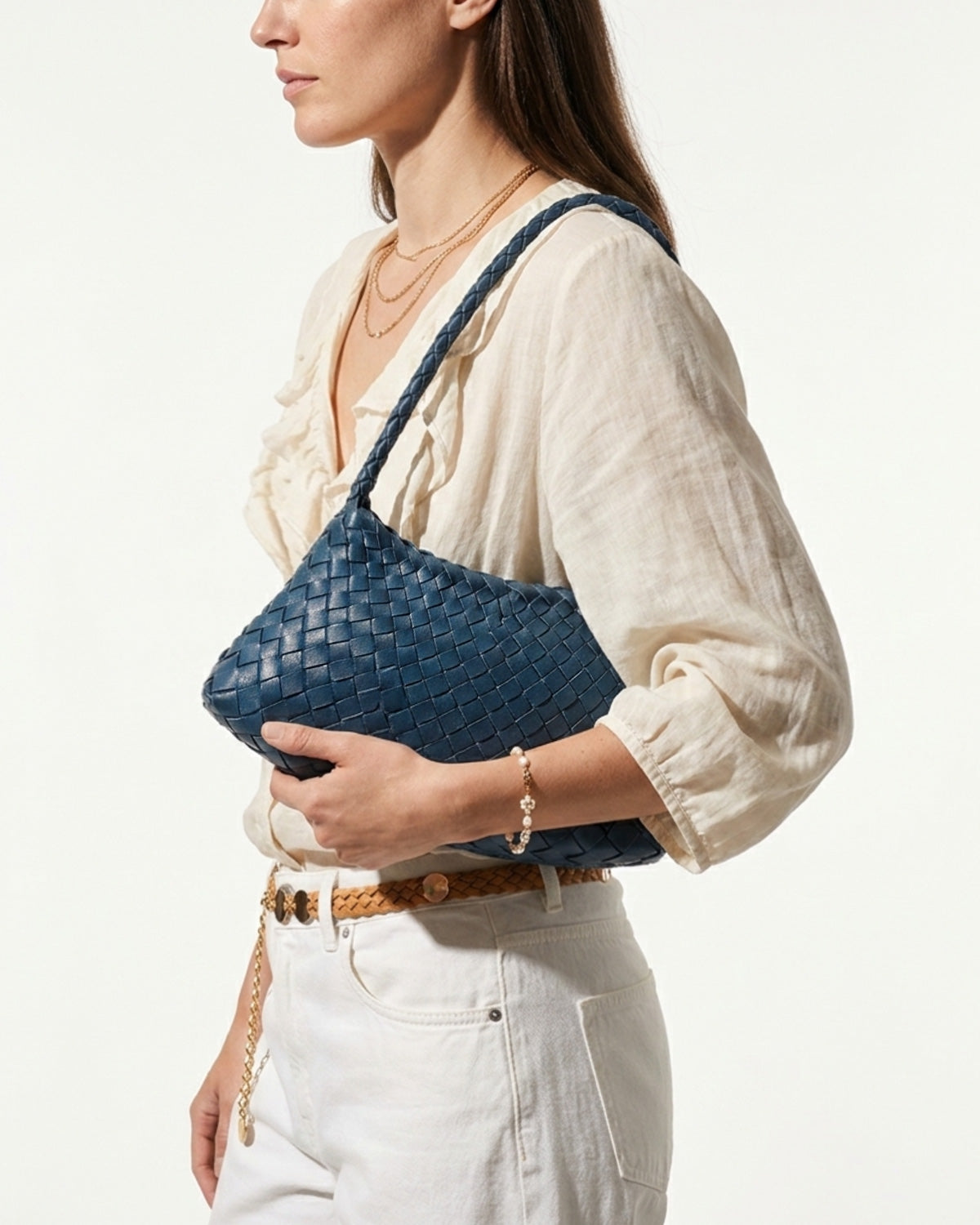 An elegant woman in a relaxed, stylish summer outfit with carries a Victoria Blue Vegan Leather Woven Shoulder Bag