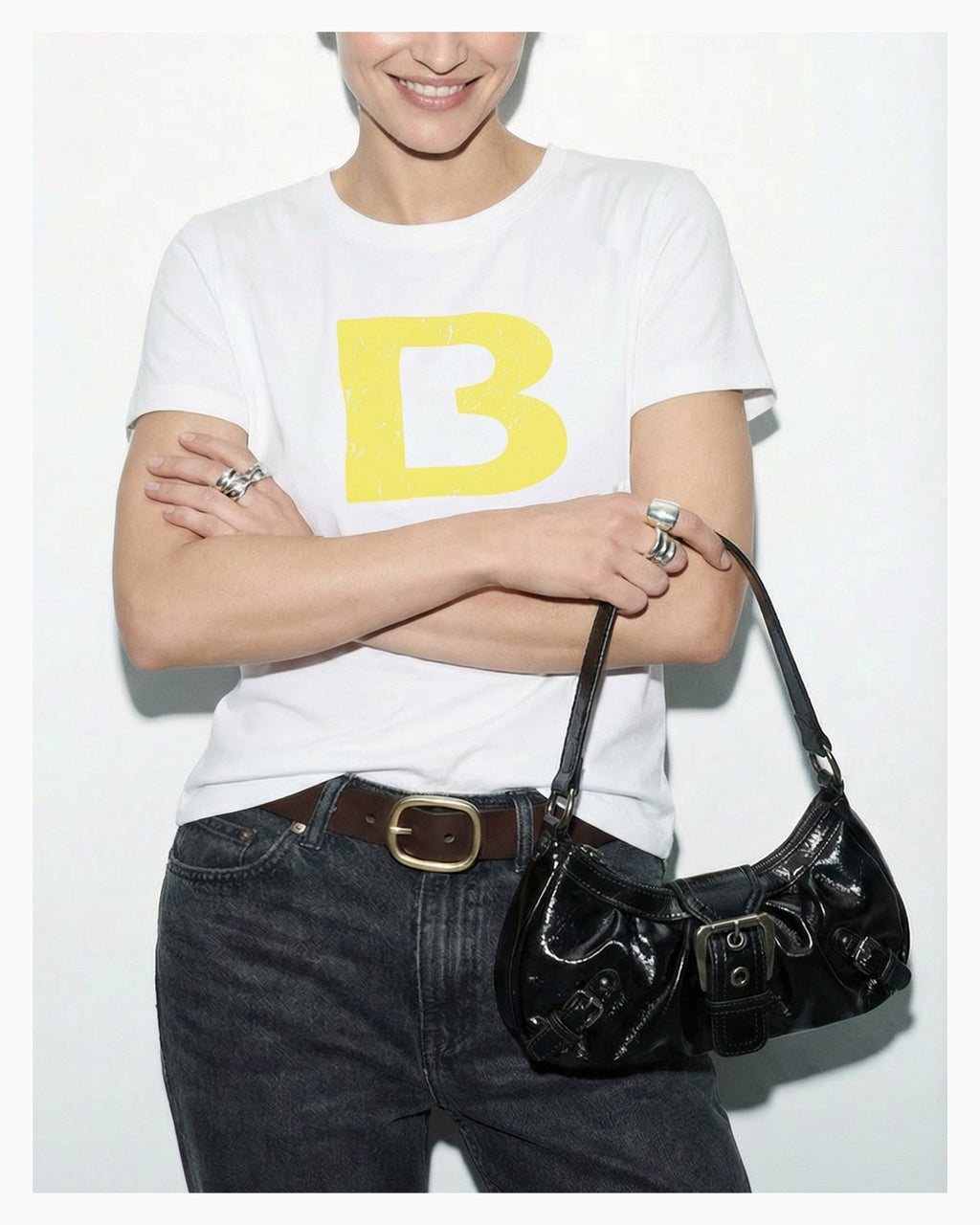 A woman in a trendy casual outfit holds a Y2K Vegan Leather Shoulder Black Bag with Buckle Detail