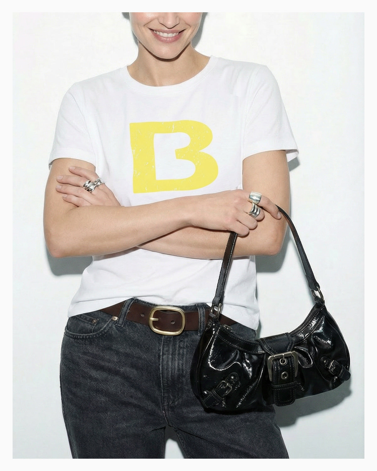A woman in a trendy casual outfit holds a Y2K Vegan Leather Shoulder Black Bag with Buckle Detail