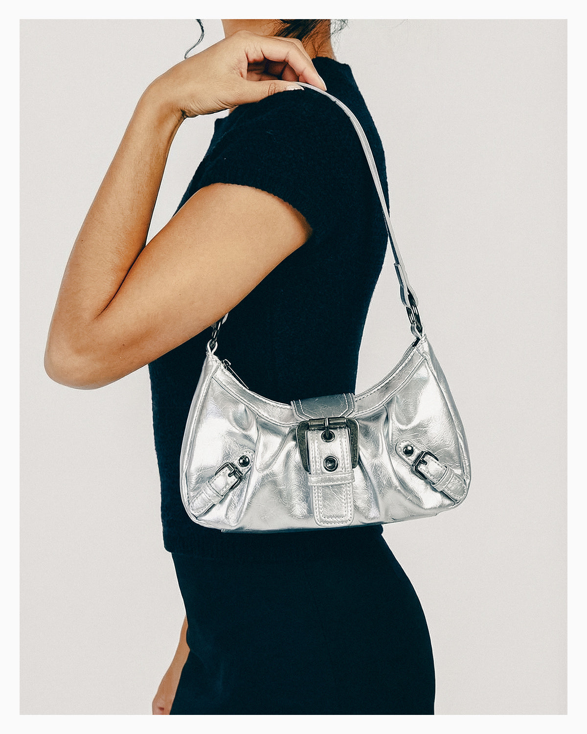 A woman in a black outfit wearing a Y2K Vegan Leather Shoulder Silver Bag with Buckle Detail