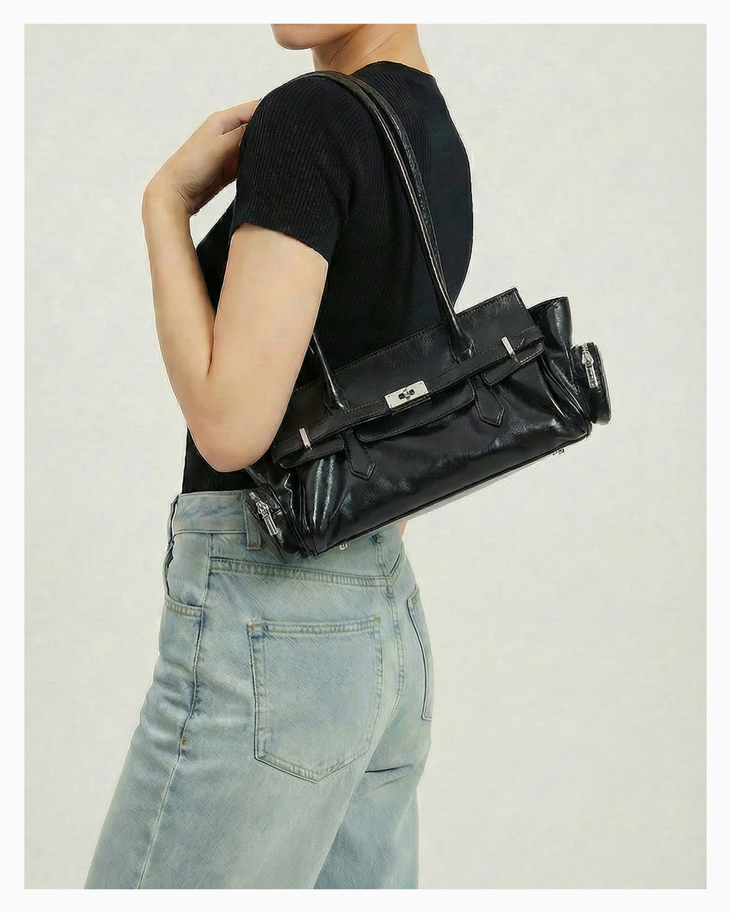 A woman in a casual outfit wearing a Genuine Leather Black Shoulder Baguette Bag with zippered side pockets and turn-lock closure