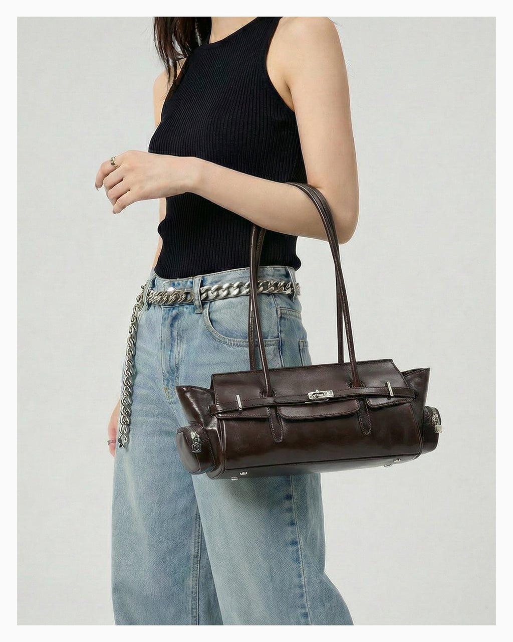 A woman in a chic casual outfit carries a Genuine Leather Shoulder Baguette Bag with zippered side pockets and turn-lock closure in Havana Color