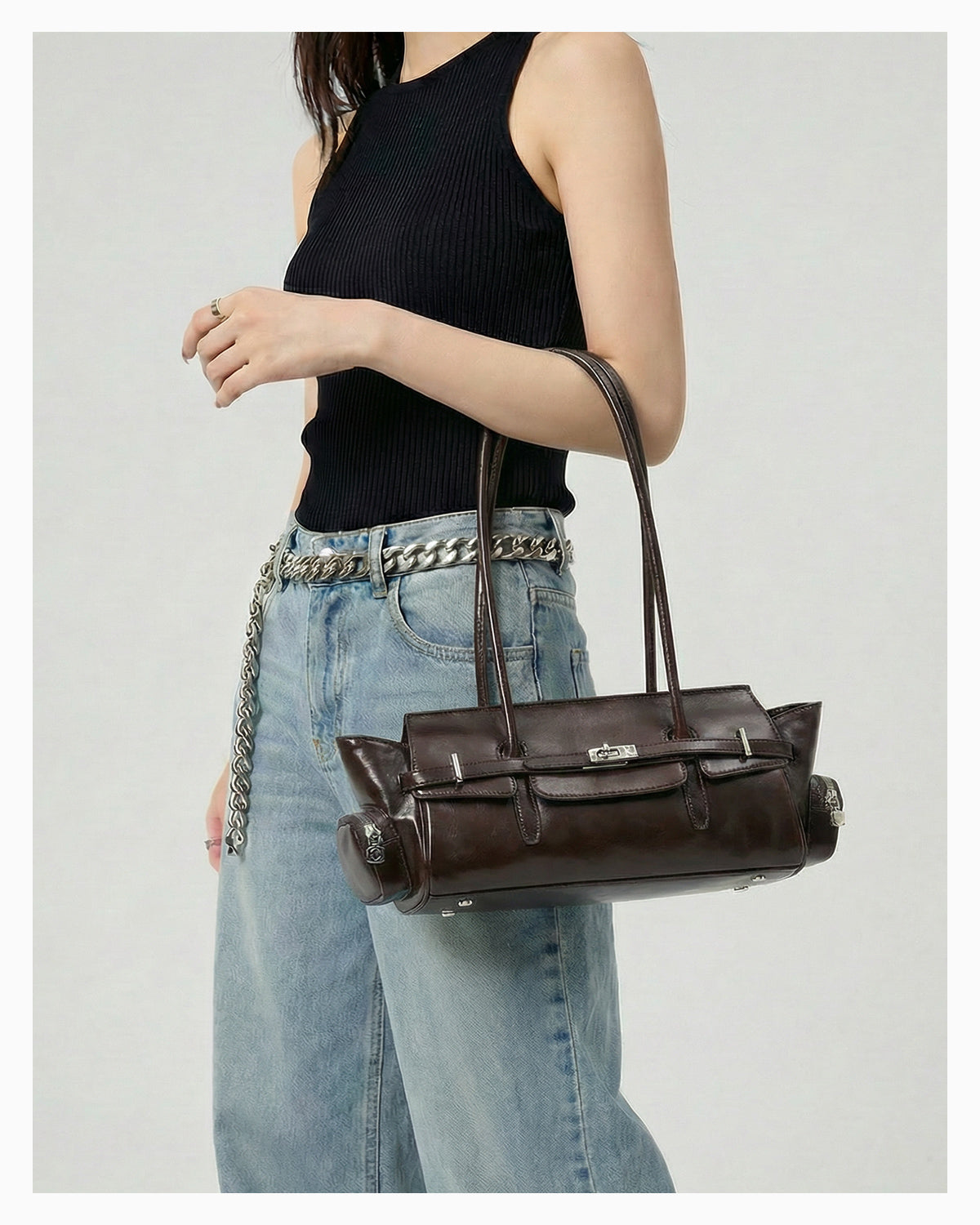 A woman in a chic casual outfit carries a Genuine Leather Shoulder Baguette Bag with zippered side pockets and turn-lock closure in Havana Color