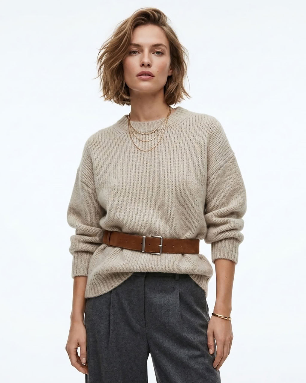A woman modeling a beige ribbed knit sweater with a caramel-colored Genuine Suede Leather Belt with Silver Rectangular Buckle, paired with dark gray trousers | BUCKLE Collective