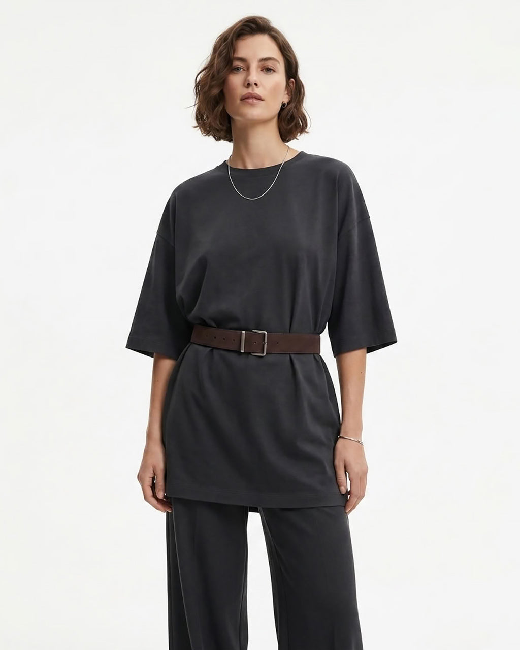 A woman modeling a dark charcoal gray short-sleeve top with a coffee-colored Suede Belt with a silver rectangular buckle, paired with matching dark gray wide-leg pants