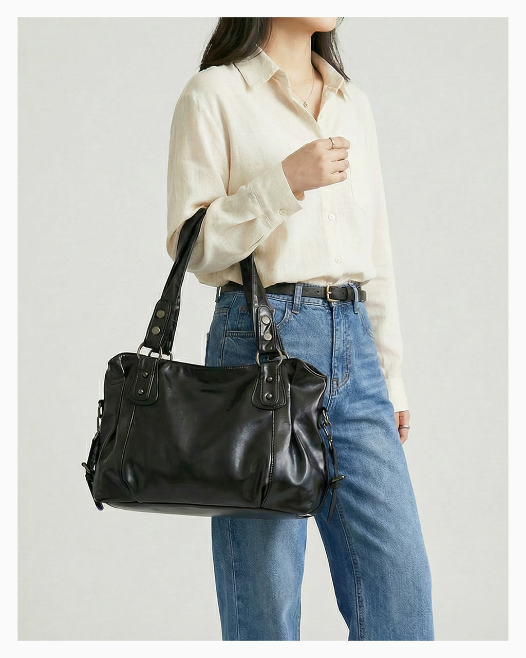 A woman in a casual outfit holds a Chic Vegan Leather Shoulder Black Bag with a Spacious Interior and Adjustable Strap