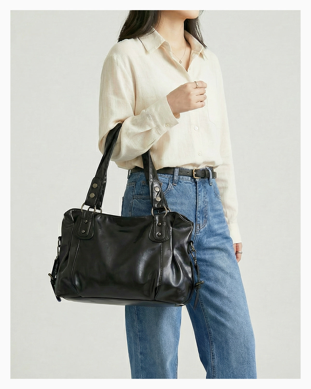 A woman in a casual outfit holds a Chic Vegan Leather Shoulder Black Bag with a Spacious Interior and Adjustable Strap
