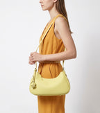 A woman in a stylish yellow-orange outfit with a Genuine Leather Crescent Baguette Shoulder Bag in a Custard Yellow Color