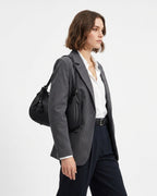 A woman in a stylish smart-casual outfit with a Genuine Leather Crescent Baguette Shoulder Bag in a black color