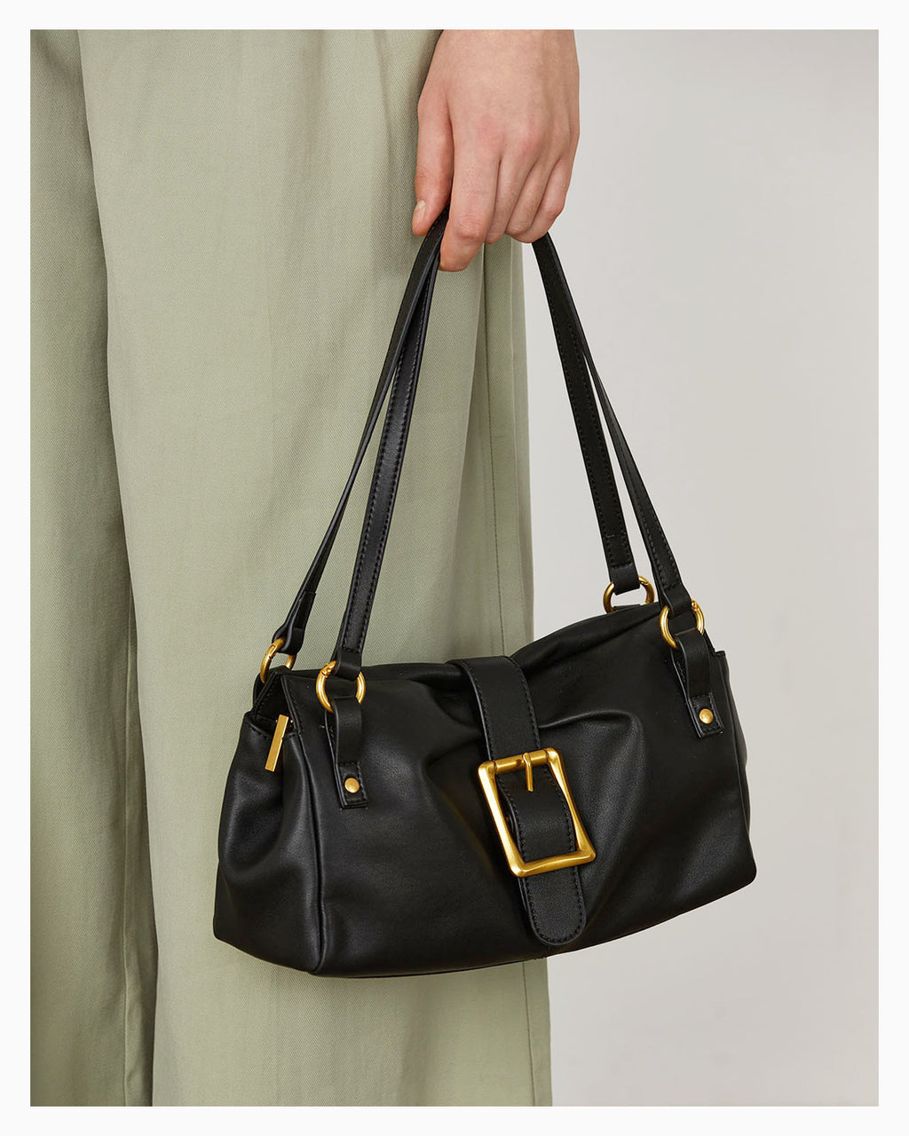 A woman holds an Elegant Versatile Leather Shoulder Black Bag with a Gold Buckle