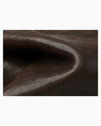 A close-up of dark brown textured leather fabric with soft folds and a smooth, slightly glossy surface.
