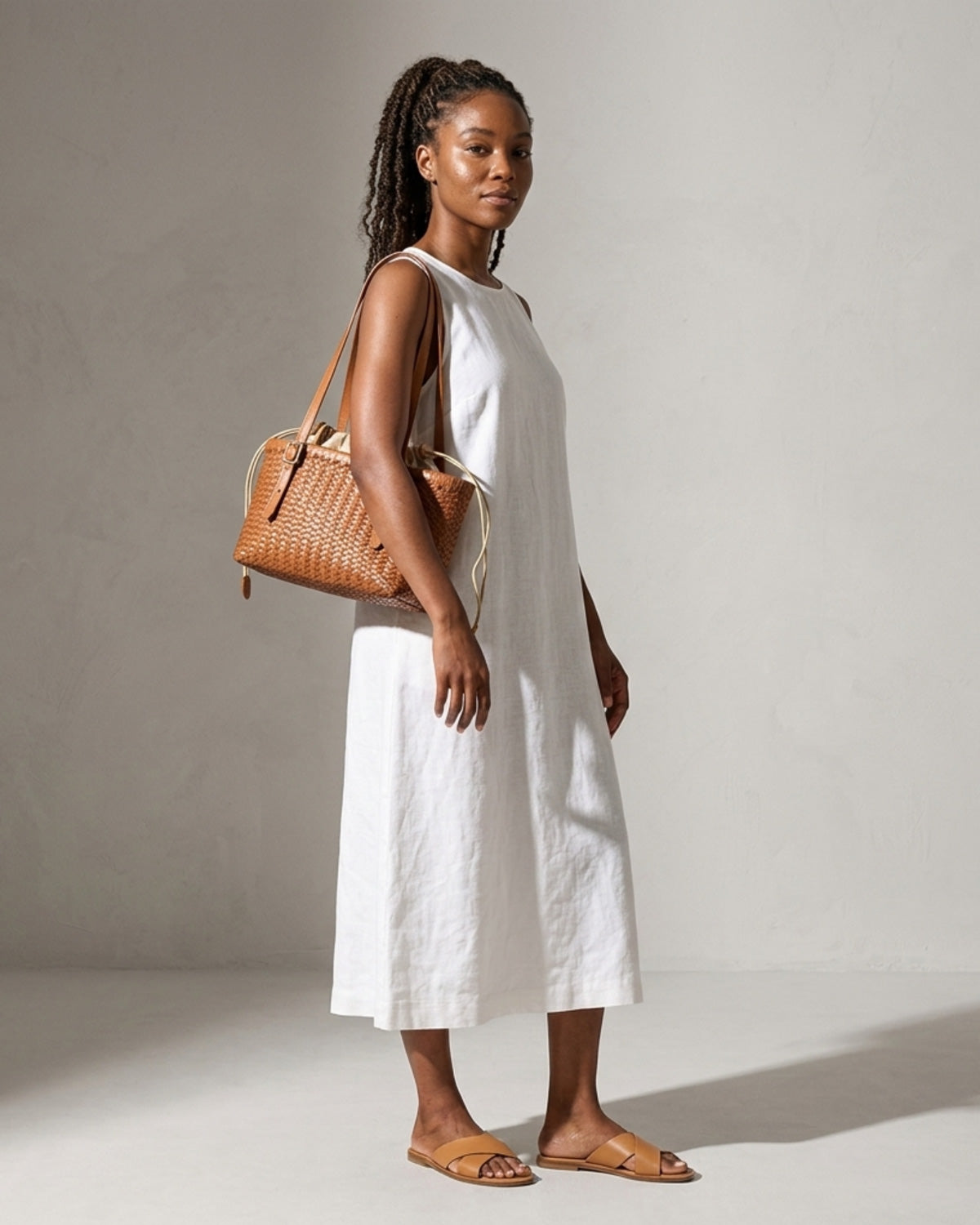 Woman in a white summer dress with trendy genuine leather Woven Tote Bucket Bag with Removable Pouch and Buckles Detail