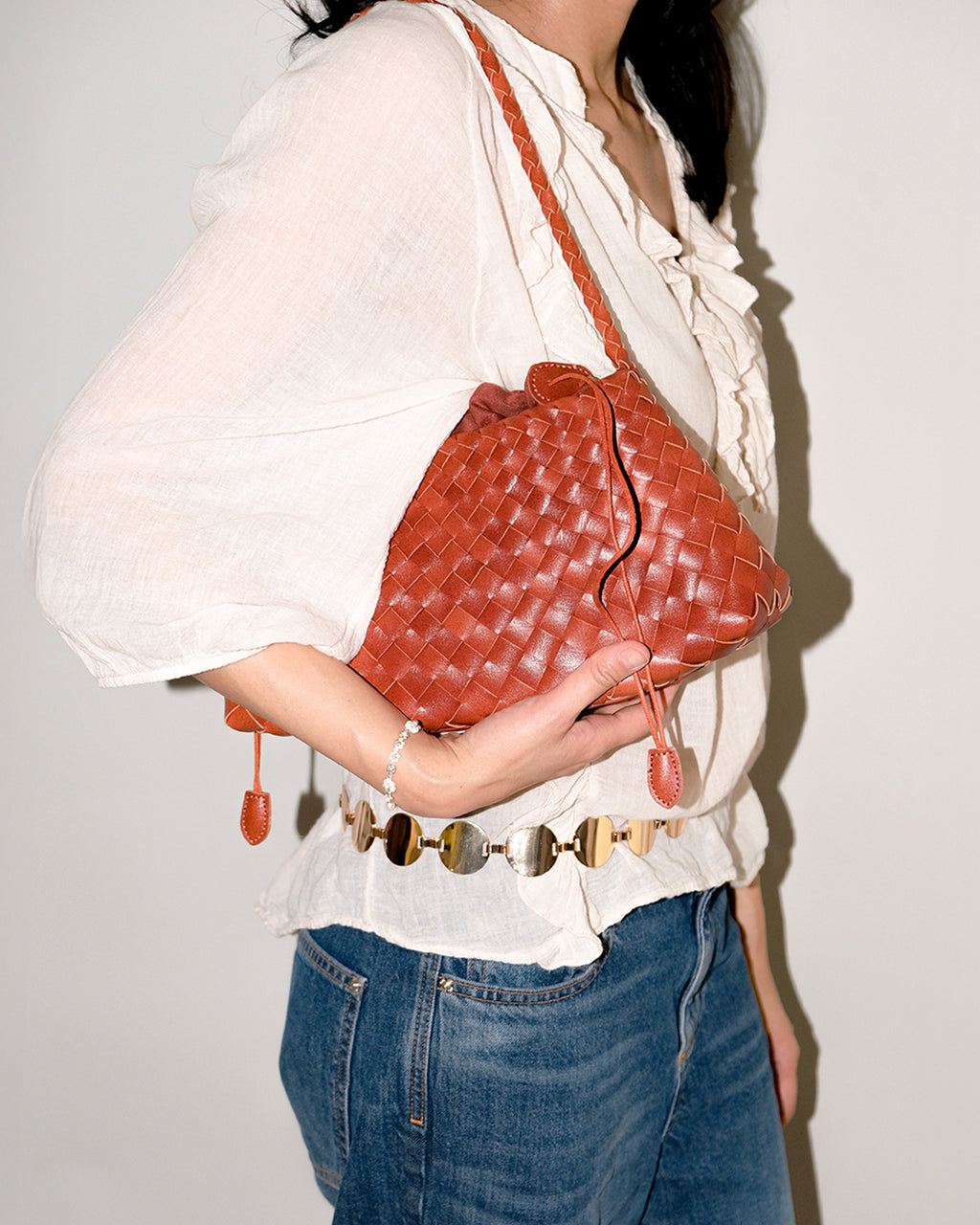 A chic woman in a casual outfit carries a trendy Vegan Faux Leather Woven Shoulder Bag in a Yellow-Brown Color