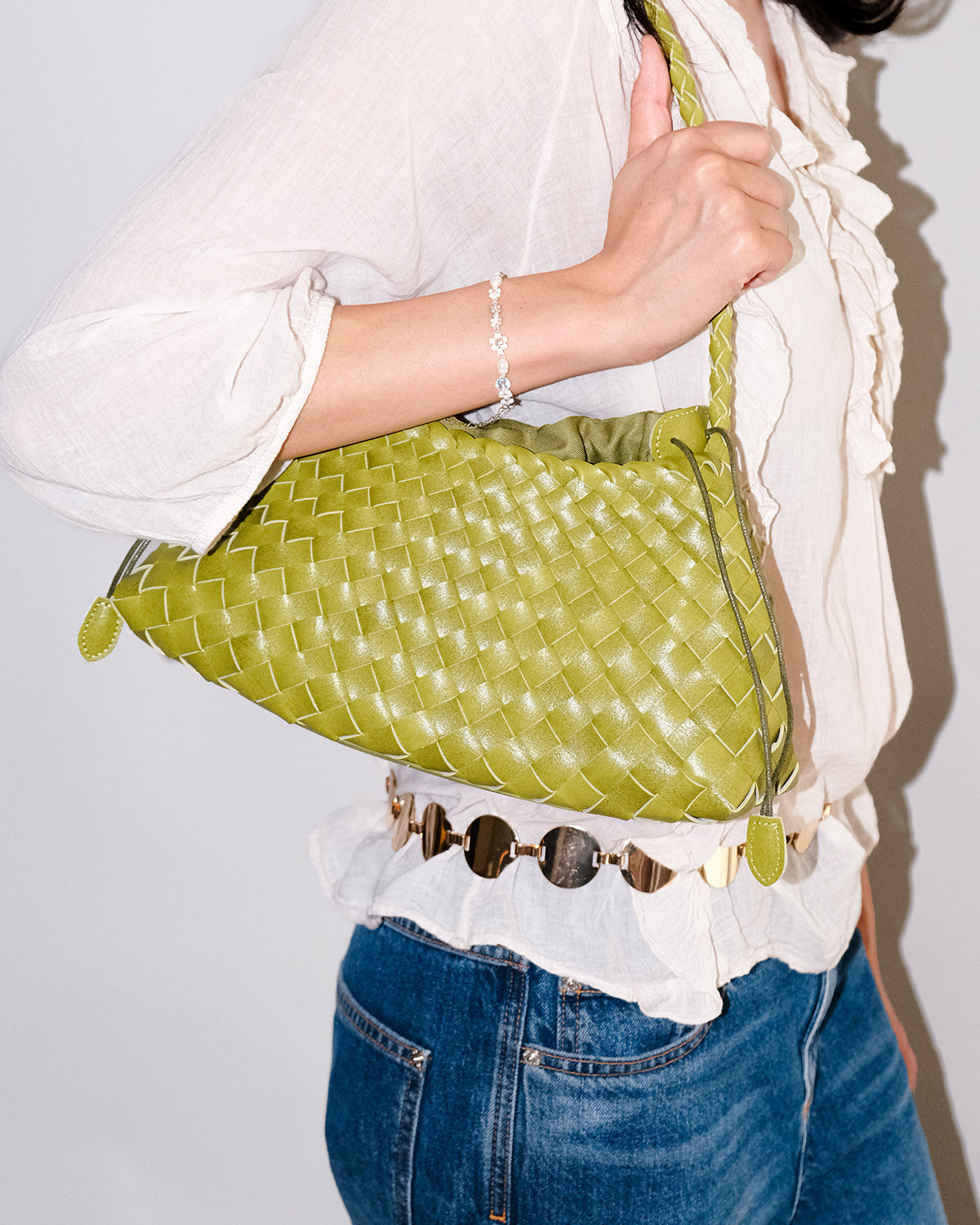 A woman in a casual summer outfit carries a trendy Vegan Leather Woven Shoulder Bag in Lime Yellow Color