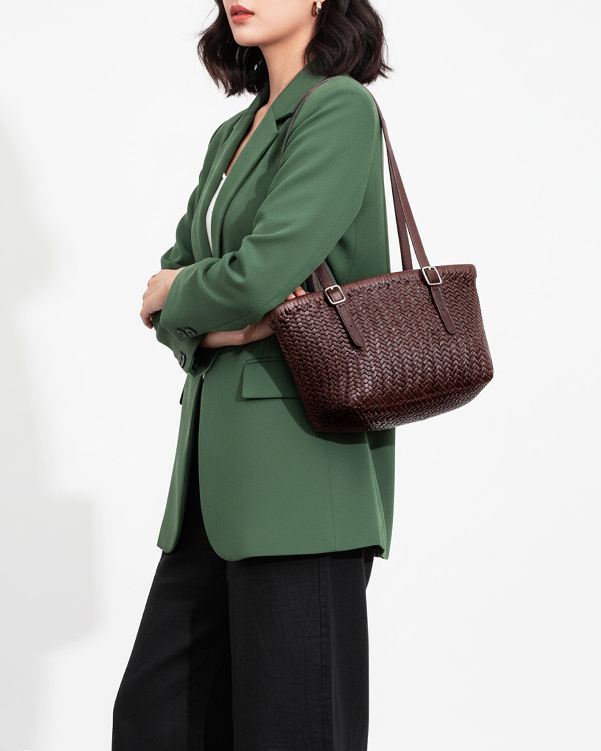 A woman in a smart-casual outfit with a Trendy Genuine Leather Woven Tote Bucket Bag with Buckle Details in Coffee Color