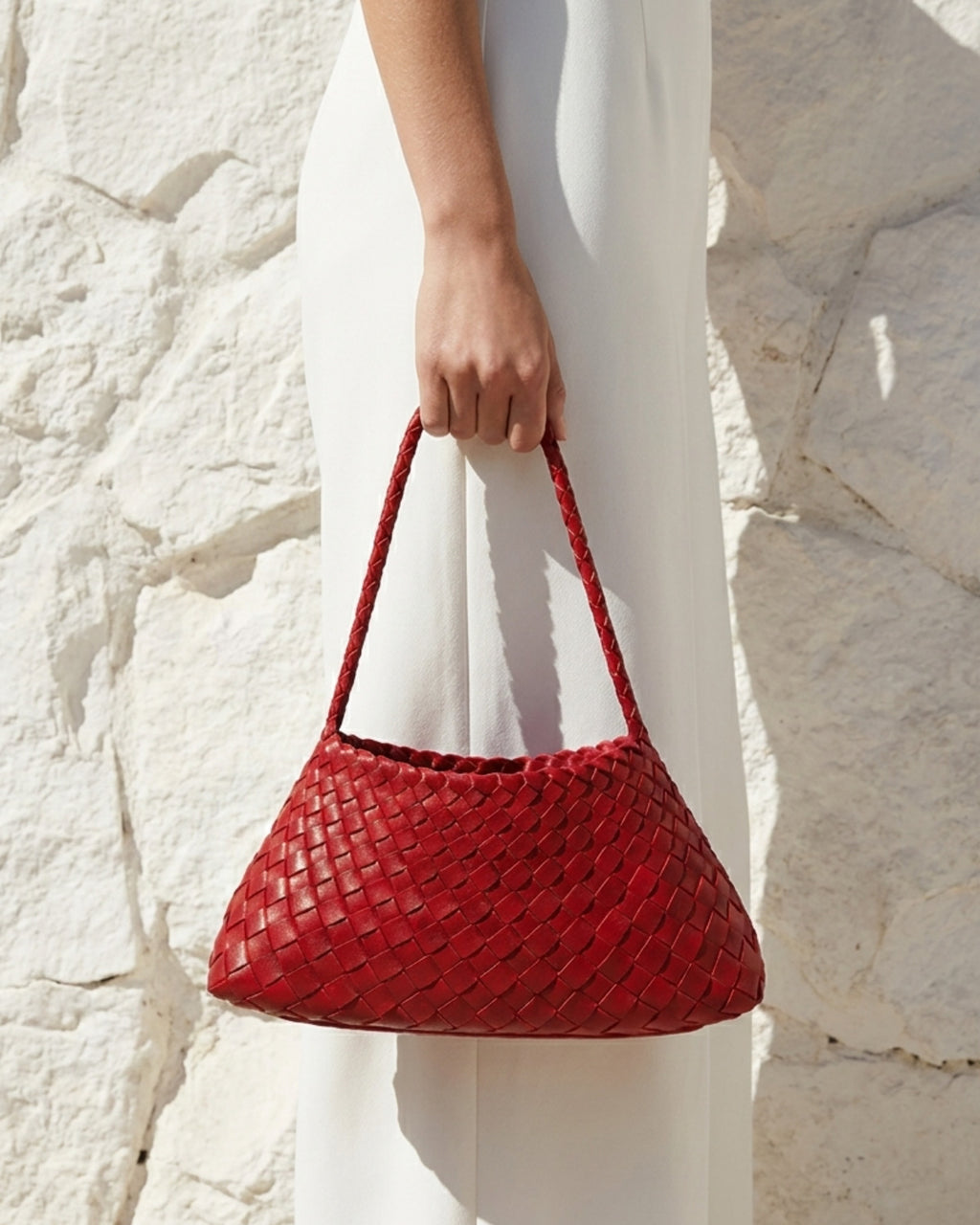 A woman in a white dress carries a Red Vegan Leather Woven Shoulder Bag