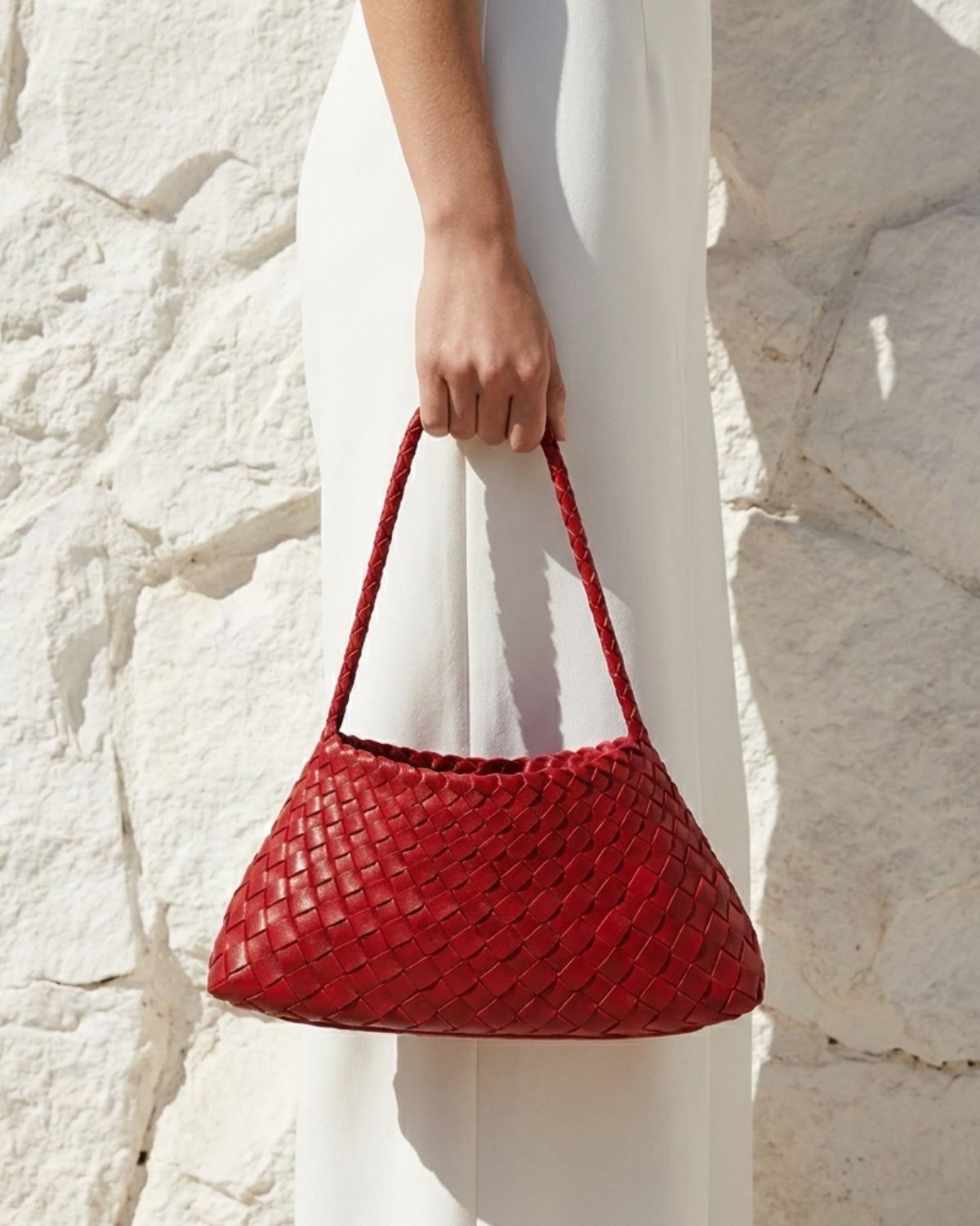 A woman in a white dress carries a Red Vegan Leather Woven Shoulder Bag